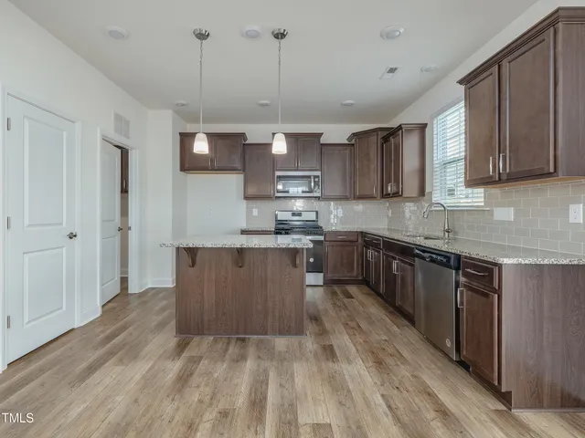 a kitchen with kitchen island granite countertop wooden floors and stainless steel appliances