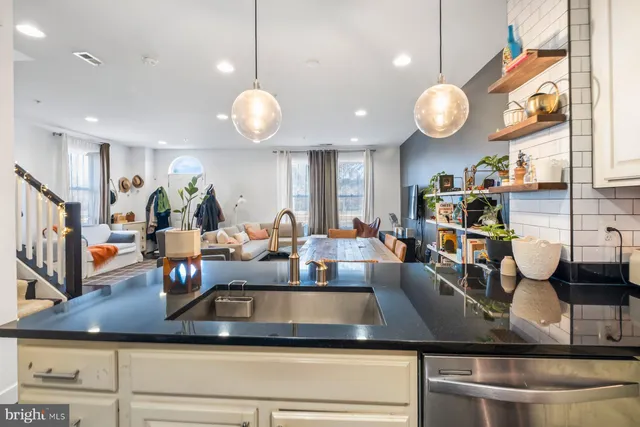a view of a counter top a dining table chairs and couches with wooden floor