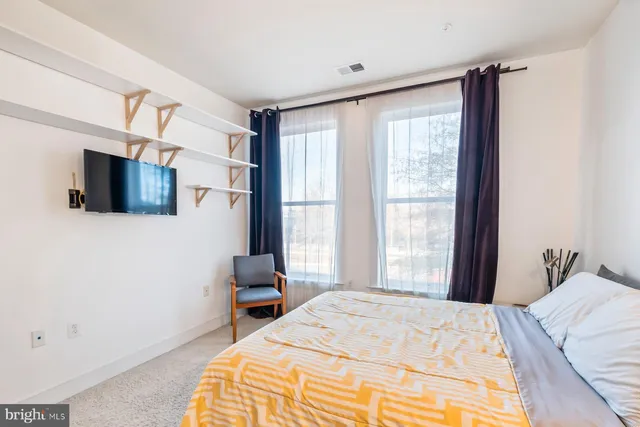 a bedroom with a bed flat screen tv and a window