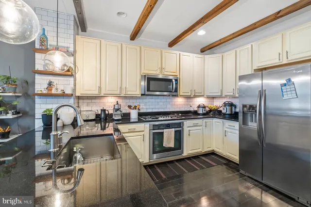 a kitchen with granite countertop a sink stainless steel appliances and cabinets