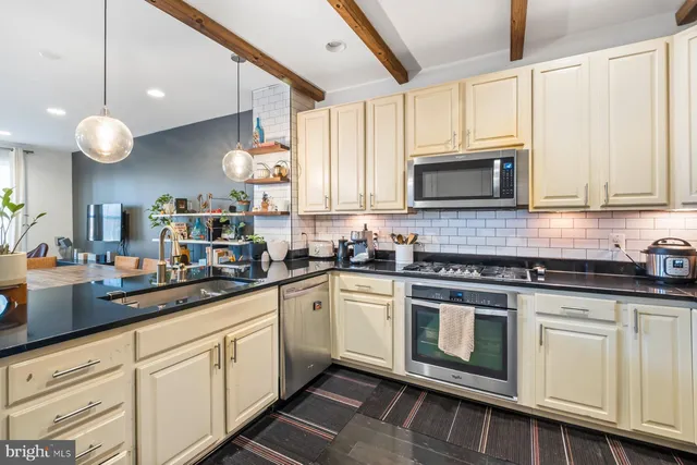 a kitchen with cabinets stainless steel appliances a sink and a window