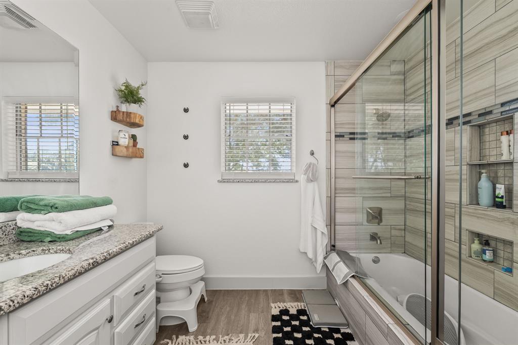 9778 Highway 11 Whitewright, TX 75491 - Photo 16 of 37 a bathroom with a granite countertop toilet a sink and a bathtub