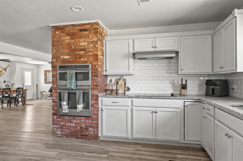 9778 Highway 11 Whitewright, TX 75491 - Photo 23 of 37 a kitchen with stainless steel appliances granite countertop a stove top oven a sink dishwasher and cabinets with wooden floor