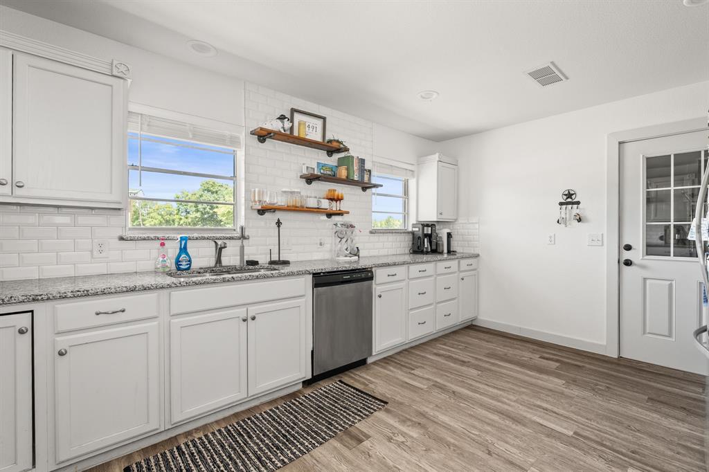 9778 Highway 11 Whitewright, TX 75491 - Photo 24 of 37 a kitchen with granite countertop white cabinets white appliances a sink and a window