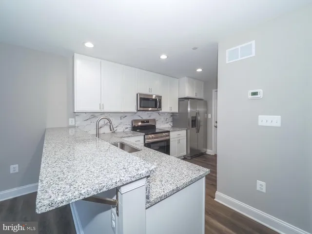 a kitchen with stainless steel appliances granite countertop a sink refrigerator and cabinets