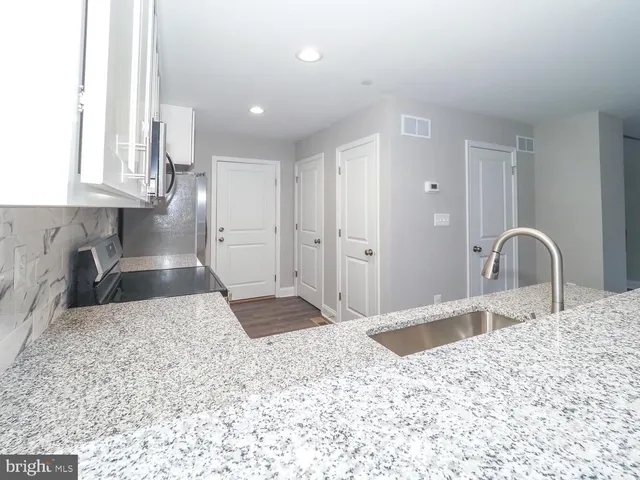 a kitchen with granite countertop a stove a sink and a microwave