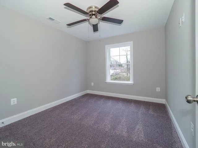 an empty room with a window and a fan