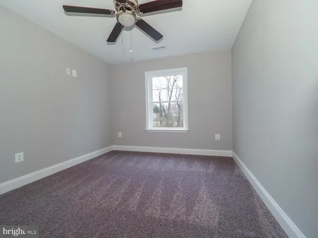 an empty room with a window and a fan