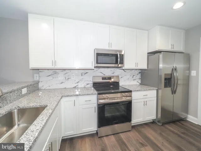 a kitchen with stainless steel appliances granite countertop a stove a sink and a refrigerator