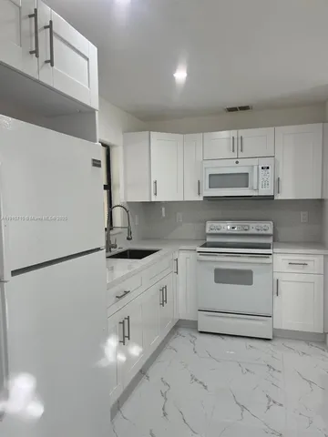 a white kitchen with cabinets and white appliances