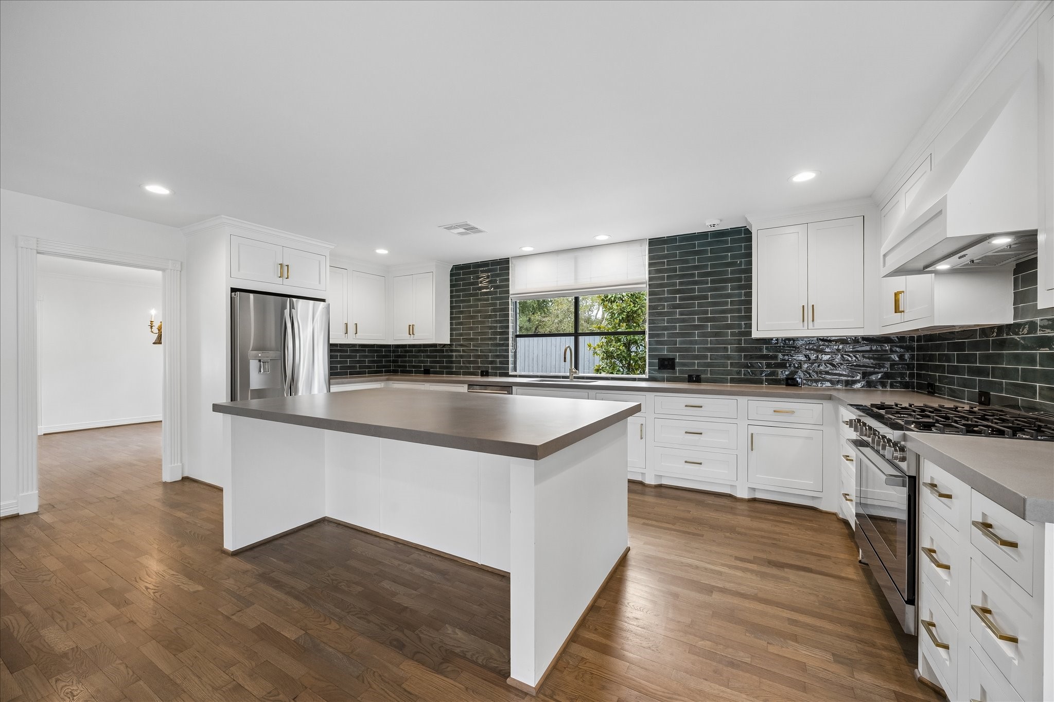 5698 Bayou Glen Road Houston, TX 77056 - Photo 7 of 30 The tastefully updated kitchen pairs crisp white cabinetry and brass hardware with striking designer green subway tile for a sophisticated pop of color.