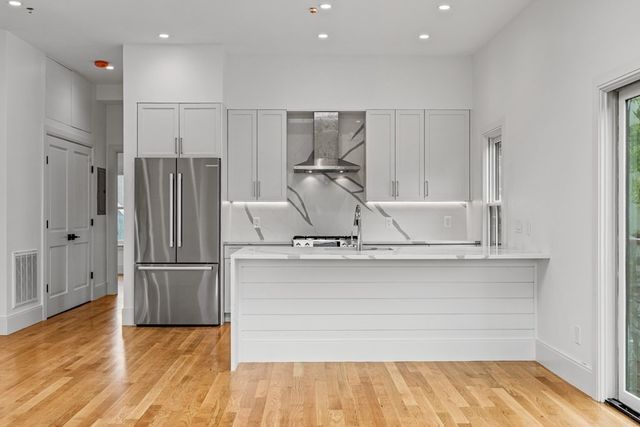 a kitchen with kitchen island a counter top space wooden floor and stainless steel appliances