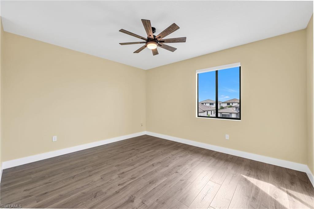 5074 Panella Avenue Immokalee, FL 34142 - Photo 26 of 48 an empty room with wooden floor and a ceiling fan