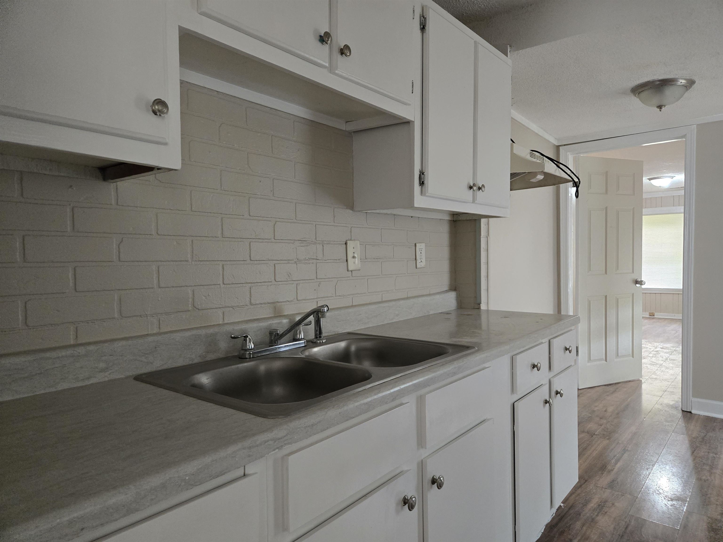 3053 Carrington Road Memphis, TN 38111 - Photo 11 of 17 Kitchen with hardwood / wood-style floors, sink, decorative backsplash, a textured ceiling, and white cabinetry
