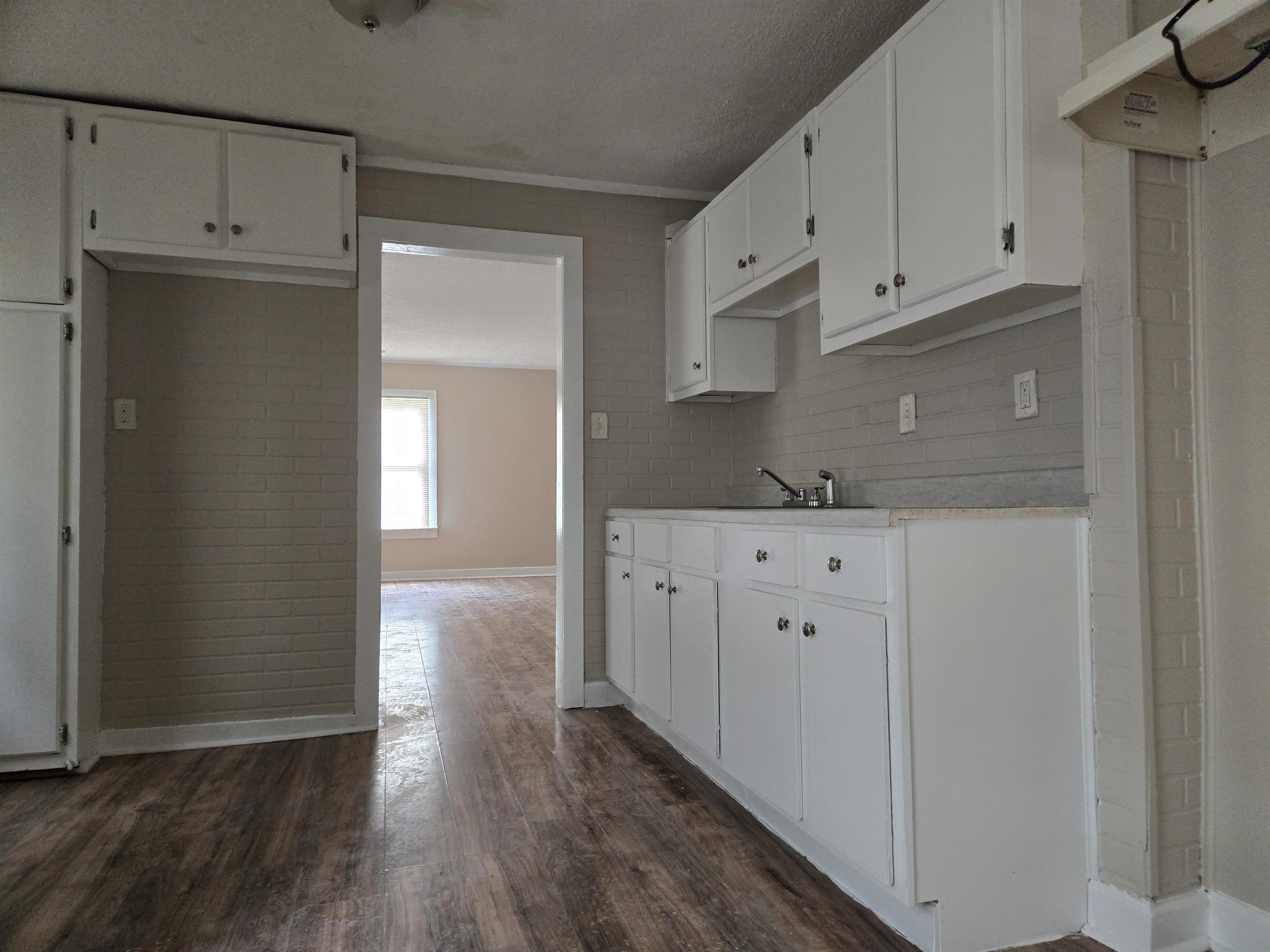 3053 Carrington Road Memphis, TN 38111 - Photo 12 of 17 Kitchen featuring sink, decorative backsplash, a textured ceiling, white cabinetry, and dark hardwood / wood-style flooring