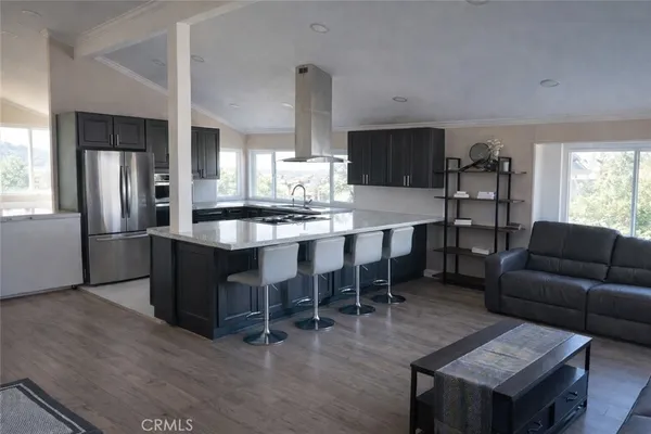 a large kitchen with stainless steel appliances kitchen island granite countertop a table chairs and a refrigerator