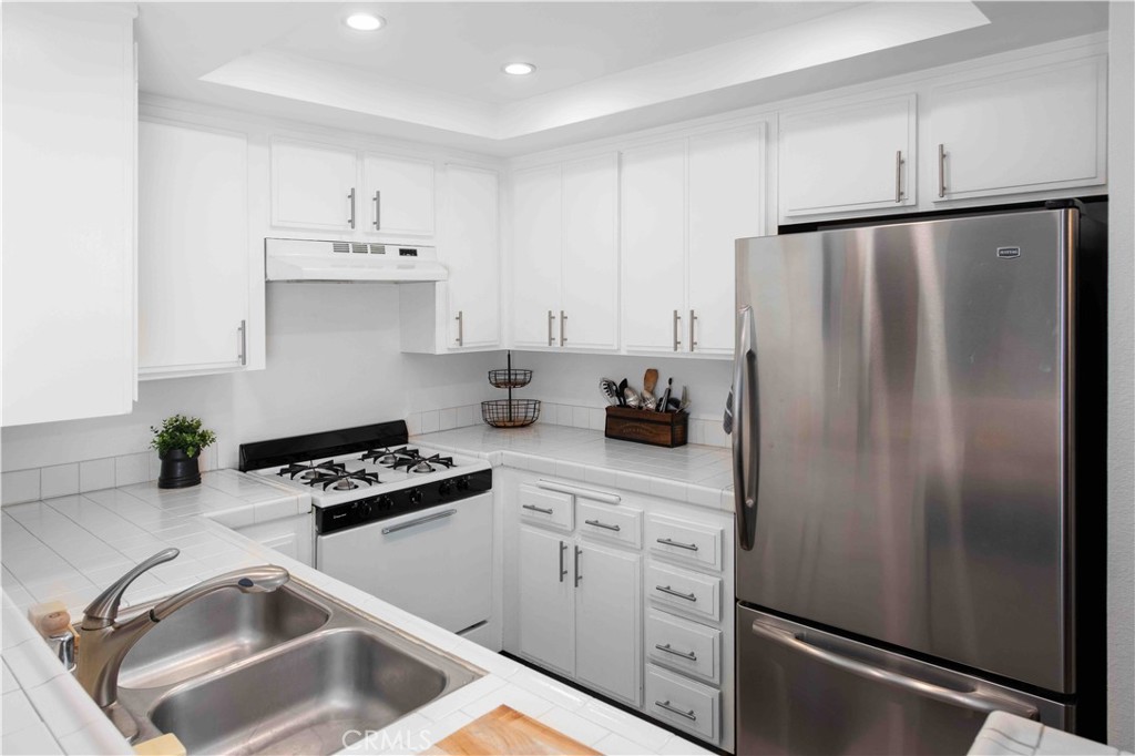 7135 Firmament Avenue, Unit 25 Van Nuys, CA 91406 - Photo 4 of 14 a kitchen with white cabinets and refrigerator