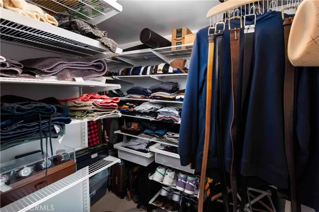 a view of walk in closet with clothes and shoes