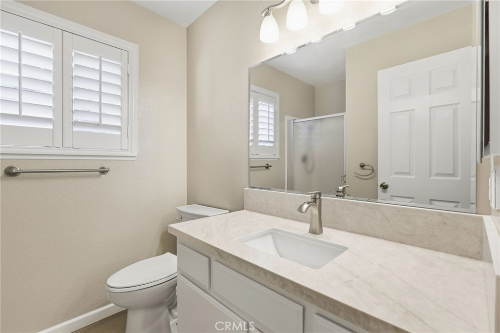 24333 Rimcrest Lane Moreno Valley, CA 92557 - Photo 21 of 62 a bathroom with a granite countertop toilet a sink and a mirror