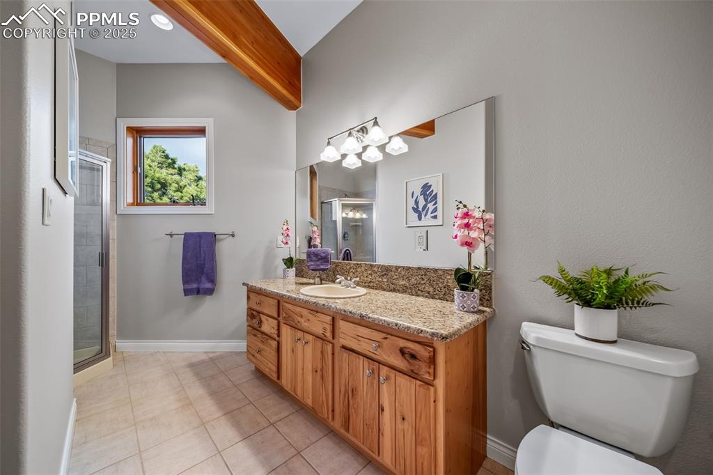 4586 East Best Road Larkspur, CO 80118 - Photo 18 of 50 Bathroom with vanity, a shower stall, light tile patterned floors, and beam ceiling
