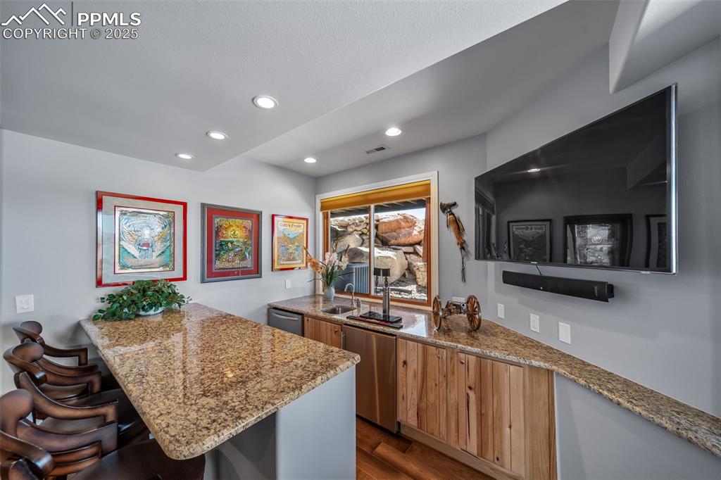 4586 East Best Road Larkspur, CO 80118 - Photo 29 of 50 Kitchen featuring a peninsula, dark wood-type flooring, a kitchen breakfast bar, light stone counters, and recessed lighting