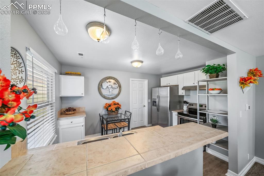 4586 East Best Road Larkspur, CO 80118 - Photo 45 of 50 Kitchen with white cabinets, pendant lighting, stainless steel range with electric cooktop, light countertops, and open shelves