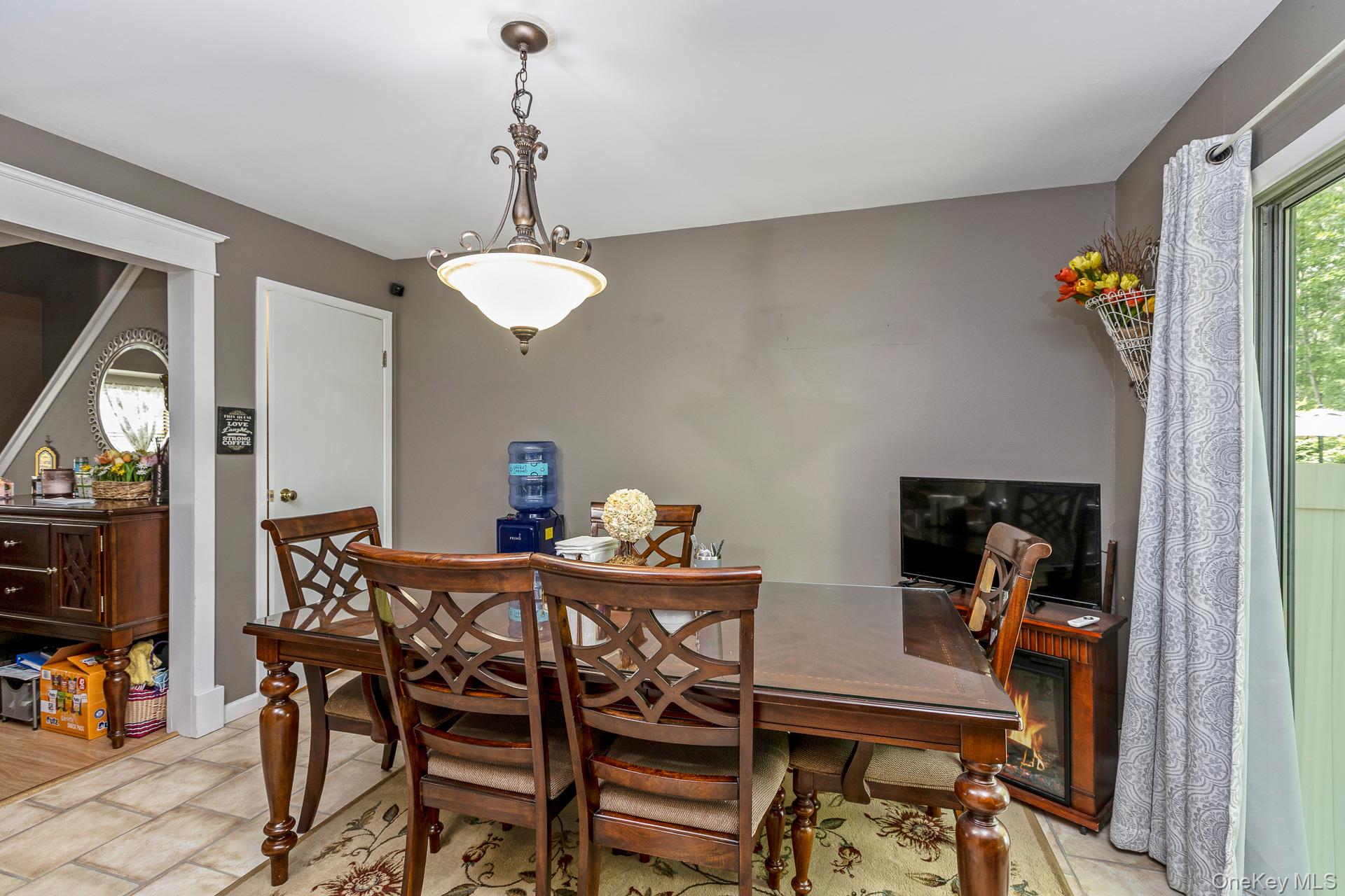 17 Stone Commons Yaphank, NY 11980 - Photo 18 of 31 Formal dining space featuring a decorative chandelier, tile flooring, and a sliding glass door to exterior
