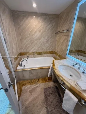 a bathroom with a tub sink and mirror