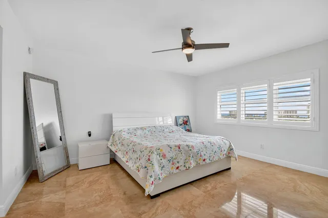 a bedroom with a large bed and a chandelier fan