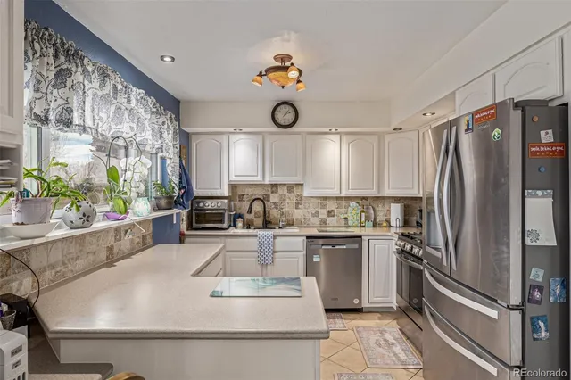 a kitchen with stainless steel appliances granite countertop a refrigerator a stove a sink dishwasher and white cabinets with wooden floor