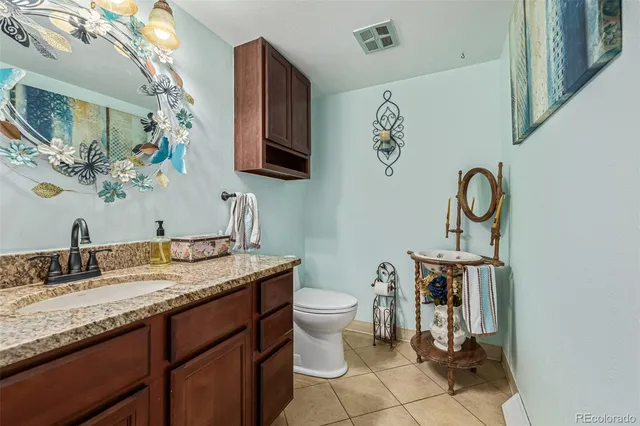 a bathroom with a granite countertop toilet sink and mirror
