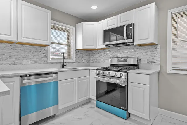 a kitchen with stainless steel appliances granite countertop white cabinets a sink and a microwave