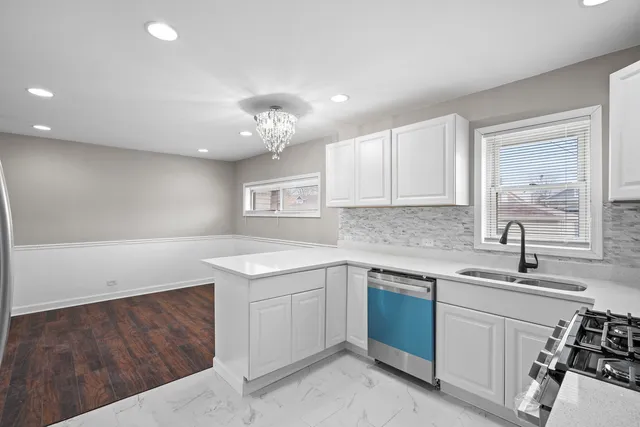 a kitchen with a sink dishwasher a stove and white cabinets