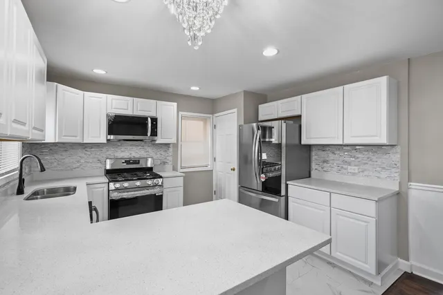 a kitchen with stainless steel appliances granite countertop a stove top oven a refrigerator a sink and dishwasher with white cabinets