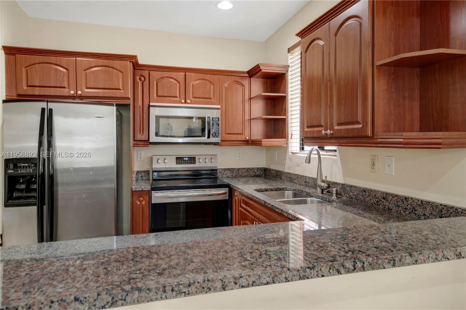 2654 Southwest 31st Place, Unit 2654 Miami, FL 33133 - Photo 3 of 17 a kitchen with stainless steel appliances granite countertop a stove a sink and a microwave