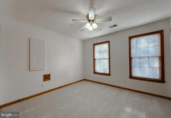 an empty room with chandelier fan and windows