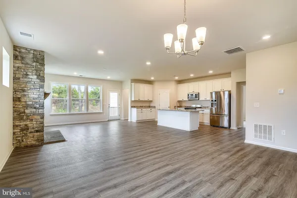 a view of a kitchen with granite countertop a stove top oven a sink dishwasher a kitchen island with wooden floor and cabinets
