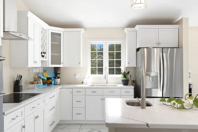 a kitchen with a refrigerator a stove a sink and chairs