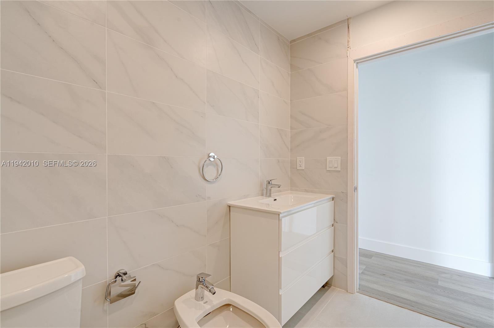 816 84th Street, Unit 2 Miami Beach, FL 33141 - Photo 10 of 19 a bathroom with a toilet a sink and mirror