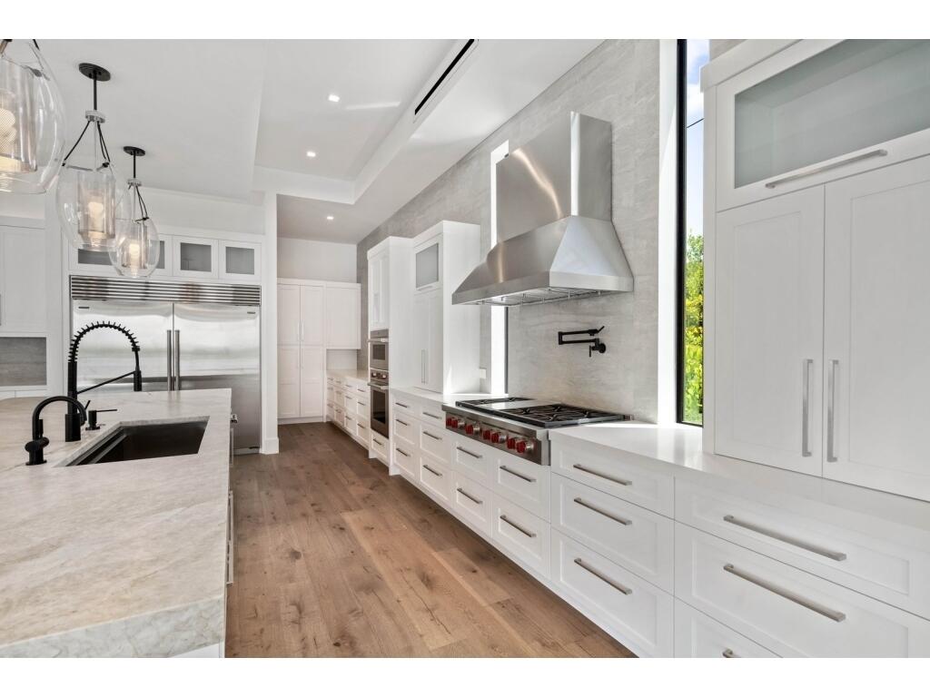 19311 North Riverside Drive Tequesta, FL 33469 - Photo 16 of 31 a kitchen with stainless steel appliances granite countertop a stove a sink and a refrigerator with wooden floors