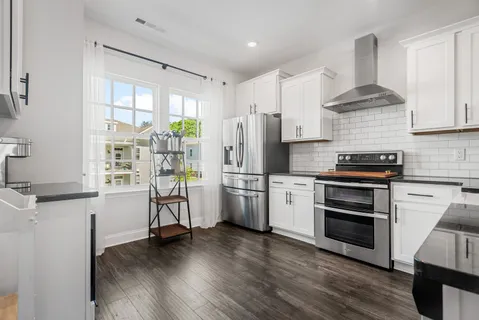 a kitchen with a refrigerator stove and wooden floor
