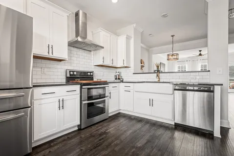 a kitchen with white cabinets stainless steel appliances and wooden floor