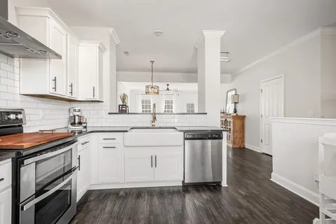 a kitchen with stainless steel appliances white cabinets and wooden floor