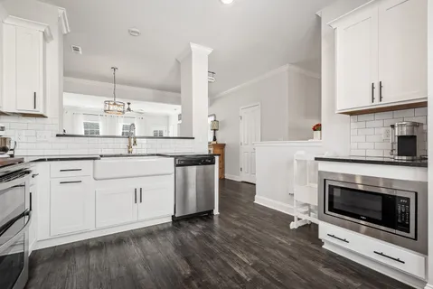 a kitchen with stainless steel appliances granite countertop a stove a sink and white cabinets