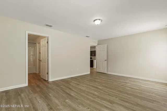 a view of an empty room with wooden floor and closet