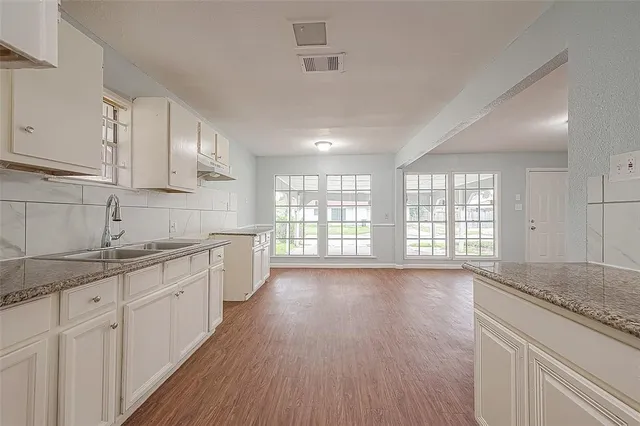 a large kitchen with granite countertop a large counter top space a sink stainless steel appliances and cabinets