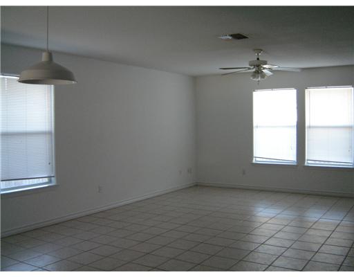 15426 Cruiser Street, Unit B Corpus Christi, TX 78418 - Photo 3 of 6 en empty room with windows and chandelier fan