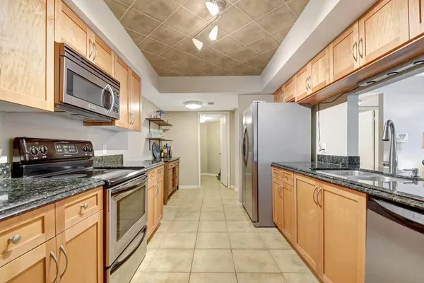 a large kitchen with stainless steel appliances granite countertop lots of counter top space and a refrigerator