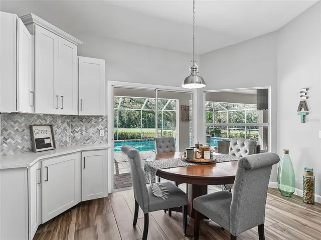 a kitchen with stainless steel appliances kitchen island granite countertop a table chairs in it and wooden floors