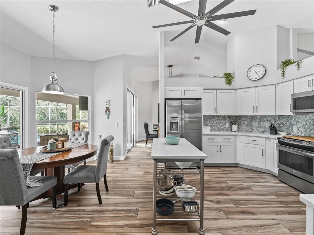 5714 Northwest 80th Ave Road Ocala, FL 34482 - Photo 12 of 39 a kitchen with stainless steel appliances kitchen island granite countertop a table chairs in it and wooden floors